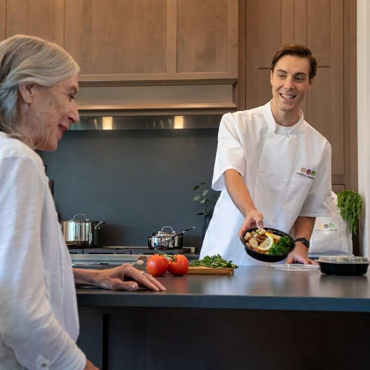 Personal chef presenting a finished meal to a client.