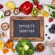 Sign reading "immunity boosters" surrounded by immune-boosting foods including peppers, kiwis, citris fruits, broccoli, garlic, blueberries, and mushrooms.