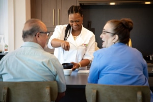 Personal chef seasoning meals in front of elderly couple.