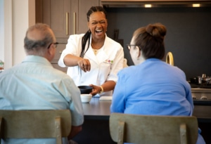 Personal chef laughing with clients in their home kitchen.