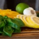Lemon and basil on a wooden cutting board.