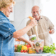 Older couple prepares fresh fruits and vegetables in kitchen