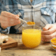 Person stirring turmeric powder into healthy drink. Turmeric root sits next to the drink on the table.